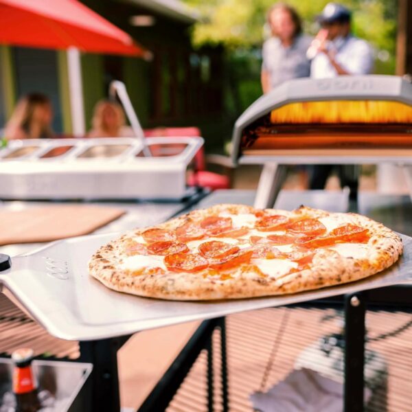 Ooni Pizza Peel removing a pepperoni pizza from the pizza oven